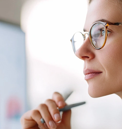 Woman with glasses looking at a digital financial data screen - Illustrative image for Financial Services AI and risk reduction solutions.